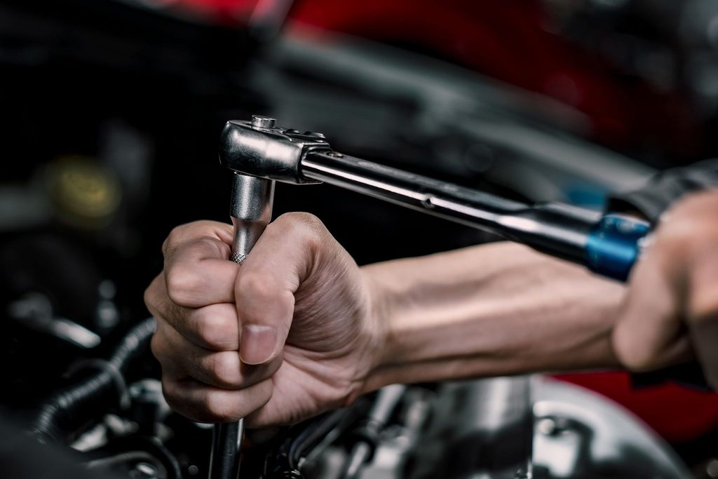 Tay kỹ thuật viên cầm cờ lê siết ốc chuyên dụng bảo dưỡng bộ phận khoang máy xe MG.